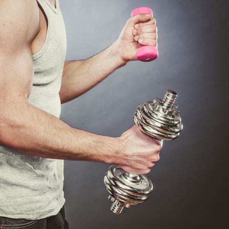 Sporty fit man lifting light and heavy dumbbells.